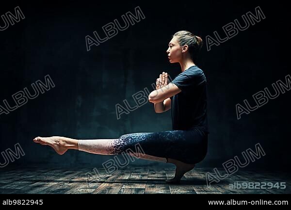 Young beautiful woman doing yoga asana tiptoe pose prapadasana