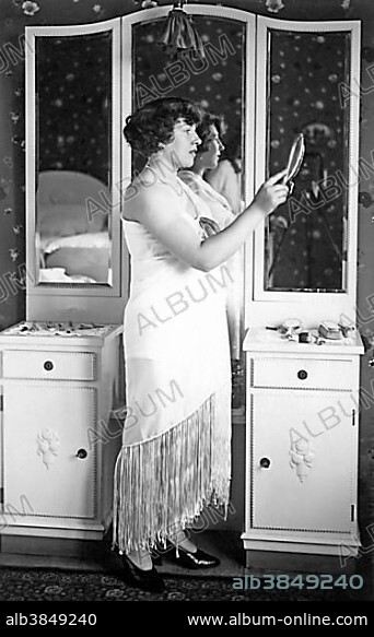 Fashion Woman in Evening Dress stands in front of a Mirror 1920s