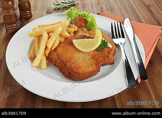 Breaded pork escalope Viennese style with lemon slice and French fries.