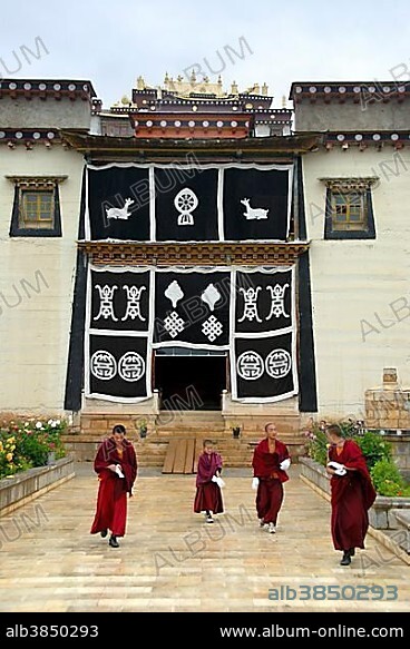 Tibetan Buddhist, monks in red robes, temple with entrance portal, religious symbols, Monastery Ganden Sumtseling Gompa, Zhongdian, Shangri-La, Yunnan Province, People's Republic of China, Asia.