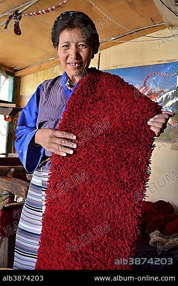 Tibetan woman wearing traditional costume, yak wool weaver holding red yak wool, Tibetan handicrafts, Lhasa, Tibet, China, Asia.