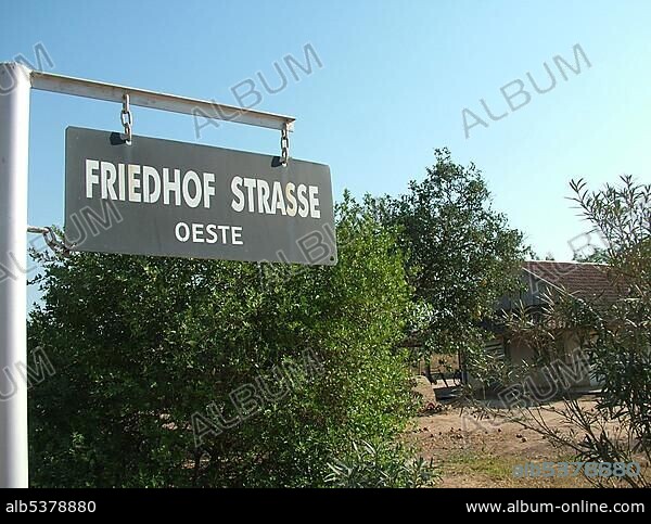 Street sign in mixed German and Spanish language in front of a