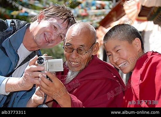 Tibetan Buddhism, tourism, portrait, joy, monk with glasses and goatee, tourist showing photo on screen of digital camera, hermitage, Yamalung Monastery near Samye, Himalayas, Tibet Autonomous Region, People's Republic of China, Asia.