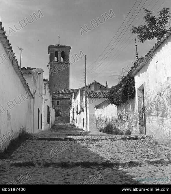 CALLE EMPEDRADA CON LA TORRE DE LA IGLESIA DE LA ASUNCION AL FONDO ...