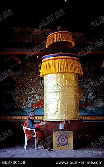 Devout Buddhist praying at a prayer wheel in Punakha Dzong, Punakha, Punakha district, Bhutan, Asia.