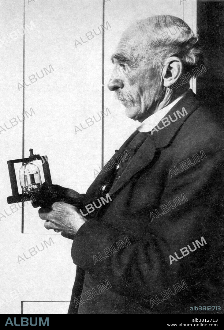 Editorial use only . Fleming, at the age of 74, holding his oscillation valve, 1923. John Ambrose Fleming (1849-1945), English electrical engineer and physicist. In 1904, he invented the two-electrode vacuum-tube rectifier, which he called the oscillation valve. It was also called a thermionic valve, vacuum diode, kenotron, thermionic tube, or Fleming valve. This invention is often considered to have been the beginning of electronics, for this was the first vacuum tube. Fleming's diode was used in radio receivers and radars for many decades afterwards, until it was superseded by solid state electronic technology more than 50 years later. He also contributed in the fields of photometry, electronics, wireless telegraphy (radio), and electrical measurements. He coined the term Power Factor to describe the true power flowing in an AC power system.