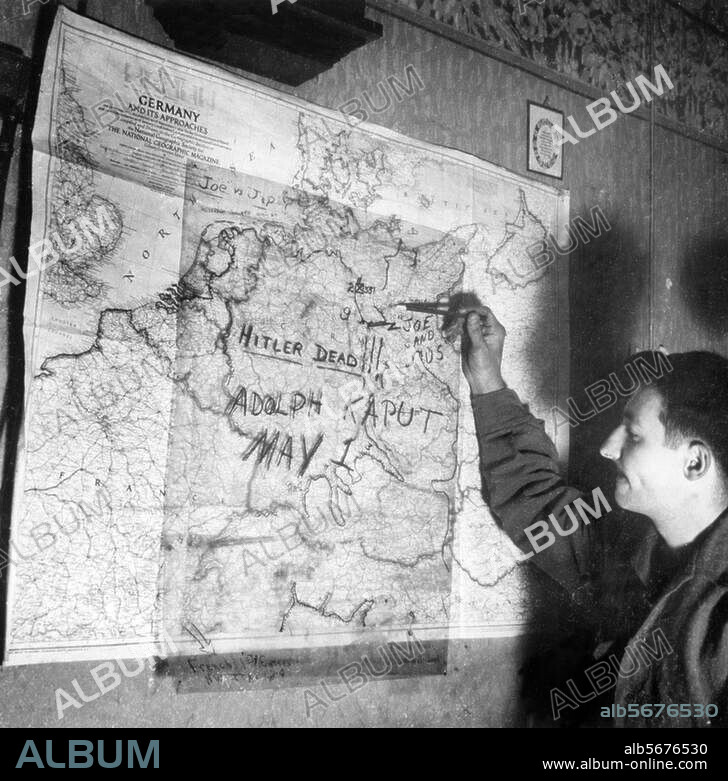 Hitler, Adolf; Dictator (NSDAP), 1889-1945. A US Soldier (Sergeant Foggle from Ohio) in front of a map of Germany with the handwritten message: "Hitler dead!! Adolph kaput, May 1". Photo, 1/5/1945.