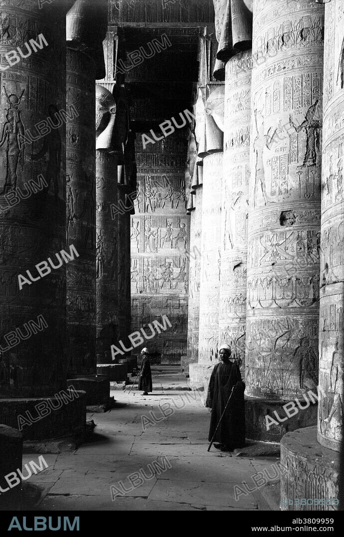 Entitled: "Temple of Hathor, Dendera. Great vestibule." Dendera Temple complex is one of the best-preserved temple complexes in Egypt. The whole complex covers almost 10 acres and is surrounded by a hefty mud brick enclosed wall. Dendera was a site for chapels or shrines from the beginning of history of ancient Egypt. The all overshadowing building in the Complex is the main temple, namely Hathor temple (historically, called the Temple of Tentyra). The temple has been modified on the same site starting as far back as the Middle Kingdom, and continuing right up until the time of the Roman emperor Trajan. The existing structure was built no later than the late Ptolemaic period. The temple, dedicated to Hathor, is one of the best preserved temples in all Egypt. Photographed by the American Colony (Jerusalem) Photo Department, 1900-20.