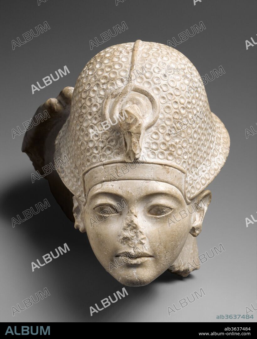 Head of Tutankhamun. Dimensions: H. 17.2 cm (6 3/4 in.); W. 16 cm (6 5/16 in.); D. 23.6 cm (9 5/16 in.). Dynasty: Dynasty 18. Reign: reign of Tutankhamun. Date: ca. 1336-1327 B.C..
This head is a fragment from a statue group that represented a god seated on a throne with the young king Tutankhamun in front of him. The king's figure was considerably smaller than that of the god, indicating his subordinate status in the presence of the deity. All that remains of the god is his right hand, which touches the back of the king's crown in a gesture that signifies Tutankhamun's investiture as king. During coronation rituals, various types of crowns were put on the king's head. The type represented here--probably a leather helmet with metal disks sewn onto it--was generally painted blue, and is commonly called the "blue crown." The ancient name was khepresh.
Statue groups showing a king together with gods had been created since the Old Kingdom, and formal groups relating to the pharaoh's coronation were dedicated at Karnak by Hatshepsut and other rulers of Dynasty 18. The Metropolitan's head of Tutankhamun with the hand of the god is special because of the intimacy with which the subject is treated. The face of the king expresses a touching youthful earnestness, and the hand of the god is raised toward his crown with gentle care.
A cast of the head has recently been matched by a scholar to the remains of an indurated limestone seated statue of a god in the storerooms at Karnak in Thebes. She reports that the join is minimal, but conclusive. This confirms the long supposed origin of the Museum's head from Karnak temple, and also resolves the question of the young king's pose - he was standing rather than kneeling in front of the god. The seated god at Karnak is only preserved from the waist down and is much damaged, so that the god is not identified specificially. Amun is, however, the likely candidate.