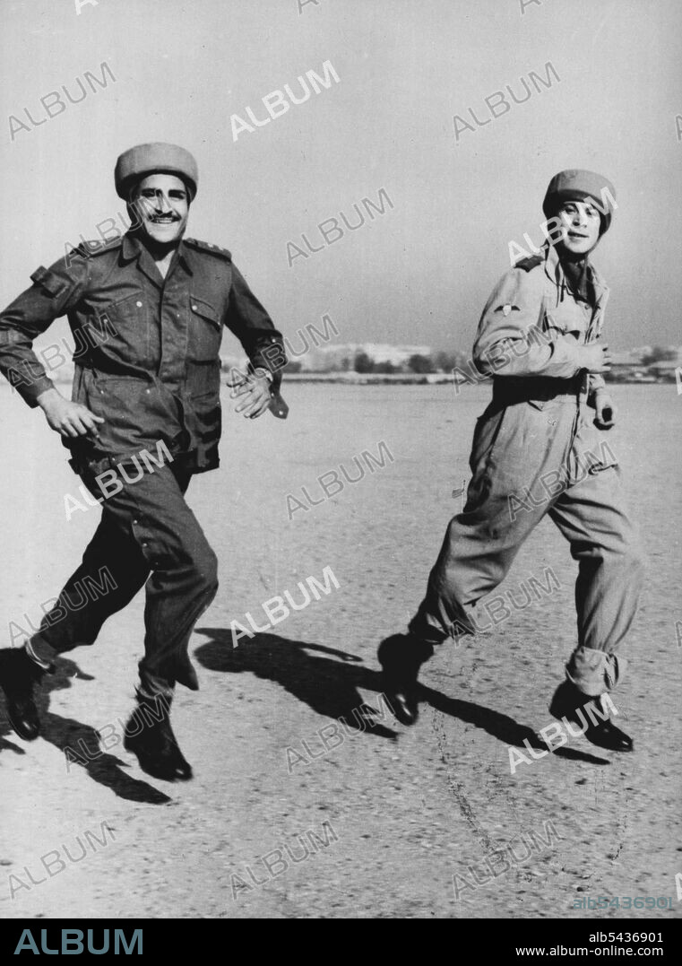 Egyptian Paratroopers Stage First Mandeuvers Captain Steimel (right, first name not available), German Instructor, runs to the waiting aircraft with an Egyptian paratrooper, during the first manoeuvres of the newly created Egyptian paratroop unit, November 29th. A Dakota aircraft of the Egyptian Royal Air Force took off from the Almaza Military Airport, with four Egyptian parachutists during the manoeuvres and later the parachutists baled out over a field. German experts who for several months h.