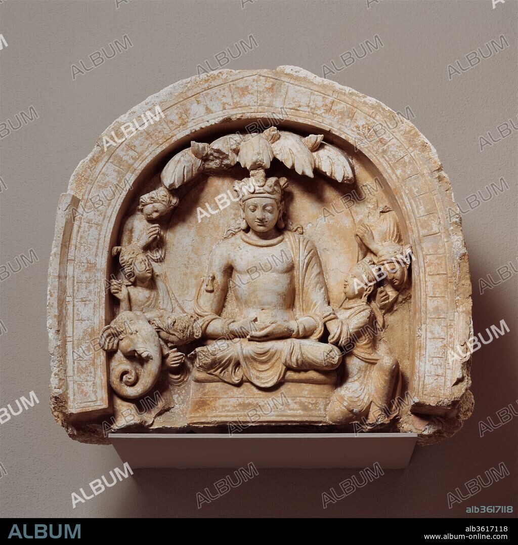 Niche with the Seated Bodhisattva Shakyamuni Flanked by Devotees and an Elephant. Culture: Afghanistan (Hadda). Dimensions: H. 16 9/16 in. (42 cm); W. 18 1/4 in. (46.4 cm); D. 10 in. (25.4 cm). Date: ca. 4th-5th century.
The lunette embellished the high base of a Buddhist stupa (relic mound) and would have been viewed from below during ritual circumnambulation. Shakyamuni is shown as a bodhisattva wearing the jeweled turban and textiles of a prince. The naturalistic anatomy and the complex classical treatment of interacting devotees seem remarkable given that the relief was sculpted about the fifth century--long after classical traditions in the West had declined.