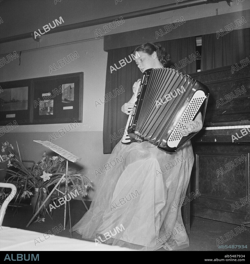 JOHN LAING PLC. John Laing and Son Limited, Page Street, Mill Hill, Barnet, London, 27/03/1953. Miss A Hatch playing an accordion at the Sports Club annual dinner. The Sports Club annual dinner was held in the canteen at Laing's Mill Hill office. Following the dinner, entertainment included a piano accordion recital, and concluded with a sing-song.