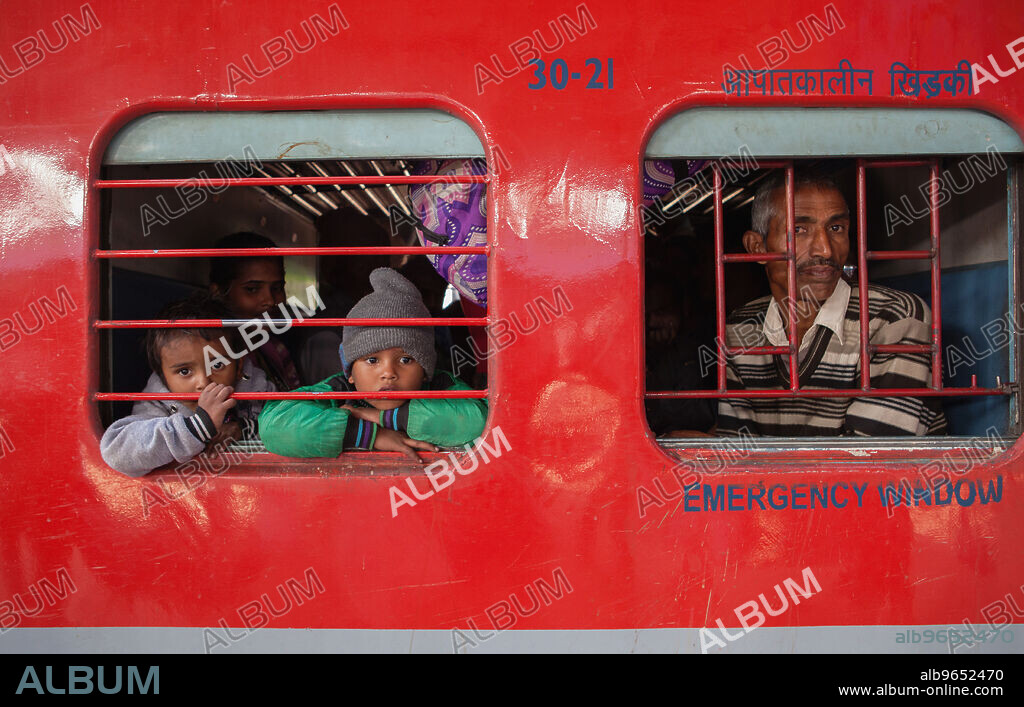 india-new-delhi-passengers-look-out-of-a-train-carriage-window-at