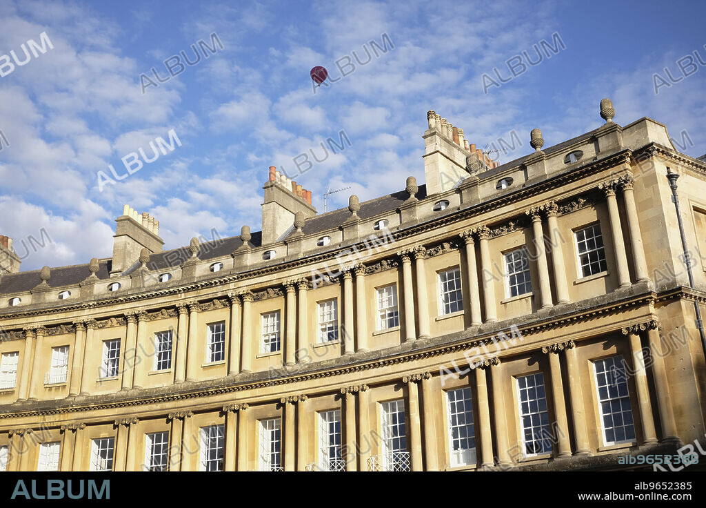 England, Bath, Exterior view of Royal Crescent with red hot air balloon in the blue sky with Cirrocumulus clouds.