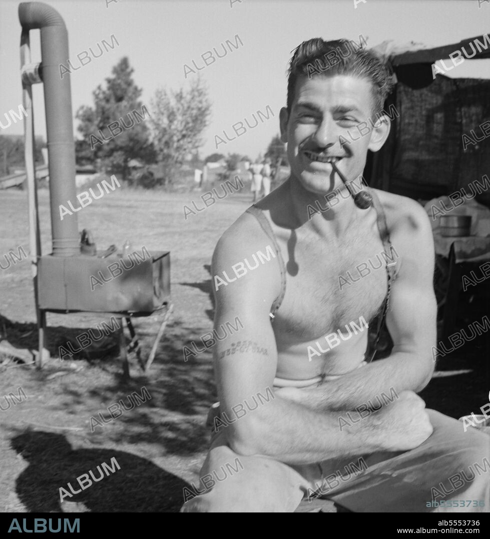 DOROTHEA LANGE. Unemployed lumber worker goes with his wife to the bean harvest. Note social security number tattooed on his arm. Oregon.