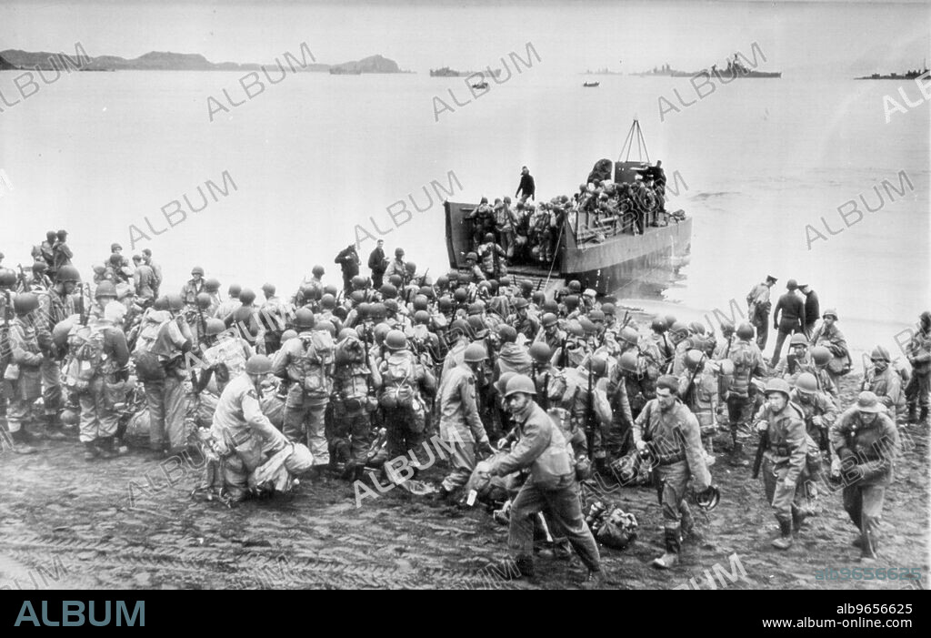 Kiska Invaders Hustle Into Landing Craft At start Of Attack -- With large naval craft standing by in the background, Allied Troops Hustle in to formation as they are loaded in to shallow-draft boat on shore of an unidentified Aleutian Island for the start of the combined American and Canadian Land, sea and air attack which resulted in the capture of the once strong Jap North Pacific base. August 21, 1943. (Photo by AP Wirephoto).