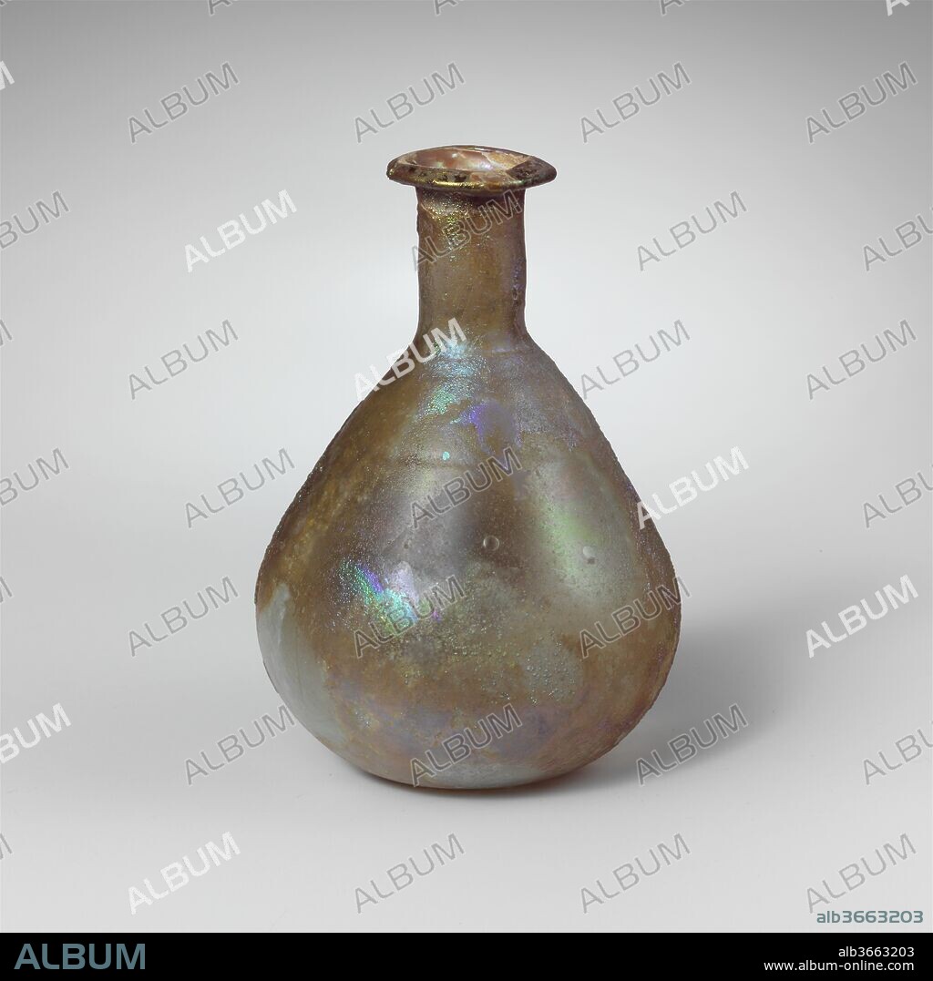 Glass perfume bottle. Culture: Roman. Dimensions: Overall: 3 5/16 in. (8.4 cm)
Diam.: 2 5/16 x 13/16 in. (5.9 x 2.1 cm). Date: 1st century A.D..
Colorless with pale blue green tinge.
Rim folded out, over, and in, with beveled upper surface; slightly flaring mouth; cylindrical neck, slightly tooled in around base; broad, ovoid body; small, slight concave bottom.
Horizontal tooled indent around upper part of body.
Intact; pinprick and a few larger bubbles; deep pitting and brilliant iridescent weathering on exterior, limy encrustation and creamy brown weathering on interior.