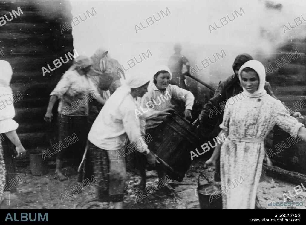 The Nazi Propaganda! on the back of the image reads: "Set on fire upon fleeing. Nearly all houses south of the strategically important village Smolensk, which was stubbornly defended by the Bolshevists, were set on fire before the withdrawal. Immediately after the German take-over of the village, the returing locals started with extinguishing works, in which our soldiers participated. It was devastating to see, how the farmers tried to save from the meagre huts as much as they could with the most primitive means." Image from the Eastern Front/Russia, 5 August 1941. The attack on the Soviet Union by the German Reich was agreed on in July 1940 and prepared as the "Operation Barbarossa" since December 1940. On 22 June 1941, the invasion by the German Wehrmacht started. Photo: Fotoarchiv für Zeitgeschichte/Archiv. 05/08/1941