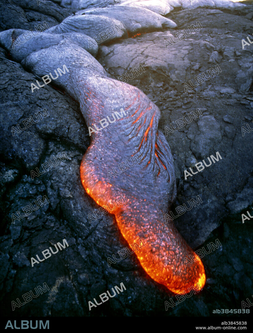 Pahoehoe lava. Molten pahoehoe lava flowing across a plain of solidified older lava. This thick ropy- looking lava may flow at speeds up to 50 kilometres per hour. Pahoehoe lava may harden in smooth sheets or it may ooze out and solidify into twisted rope-like formations. Pahoehoe lava is a type of basic lava with a low silica content, giving it a low melting point. This means the lava can travel great distances from the crater or vent from which it issued. Photographed at Kilauea Volcano, Big Island, Hawaii, USA. April 13, 1996.