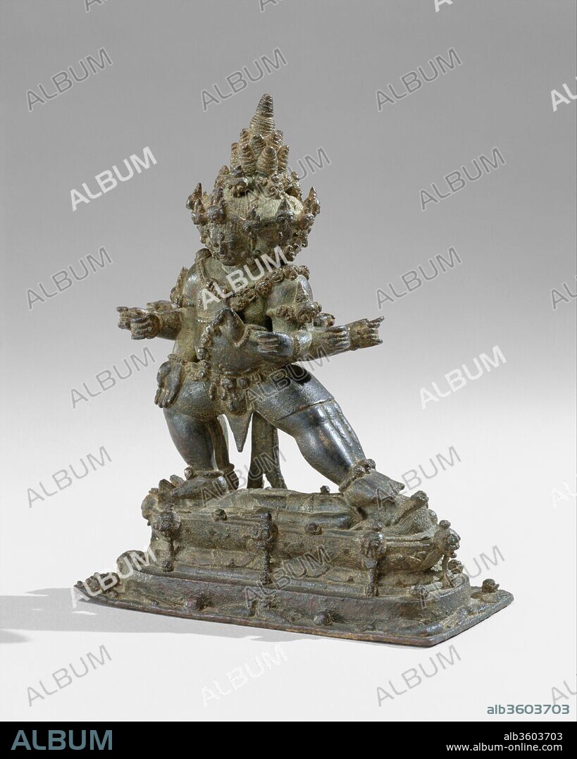 The Buddhist Guardian Mahabala. Culture: Indonesia (Java). Dimensions: H. 6 1/2 in. (16.5 cm). Date: 11th century.
According to certain traditional programs of Esoteric Buddhist iconography, Mahabala, similar to Yamantaka, is the conqueror of the lord of death and, by extension, of death itself. As a guardian of the faith (dharmapala), he is depicted as a fierce deity, shown here trampling a prostrate male, perhaps signifying death.
The powerful, corpulent protector adopts the aggressive stance of pratyalidha, a posture often used by figures trampling foes. His lowered right hand is in the boon-granting gesture and his raised left is in a sign of warning or menace. Mahabala is depicted with six heads, six legs, and twelve arms. Of the six faces, only one is pacific; the rest are wrathful, fanged, and terrifying. All of the heads wear diadems of skulls, and the deity wears a matching necklace and a sacred thread composed of skulls alternating with lotuses. Mahabala's hair is a series of spiraling conical forms, which heighten the sense of a great pyramidal mass being supported by the shoulders.
Mahabala frequents cemeteries, and his necropolitan associations--torsos, limbs, skull bones, and flayed skin--are graphically depicted around the base of the sculpture. Amid this grisly reminder of mortality, one macabre smiling head appears on the side of the base.