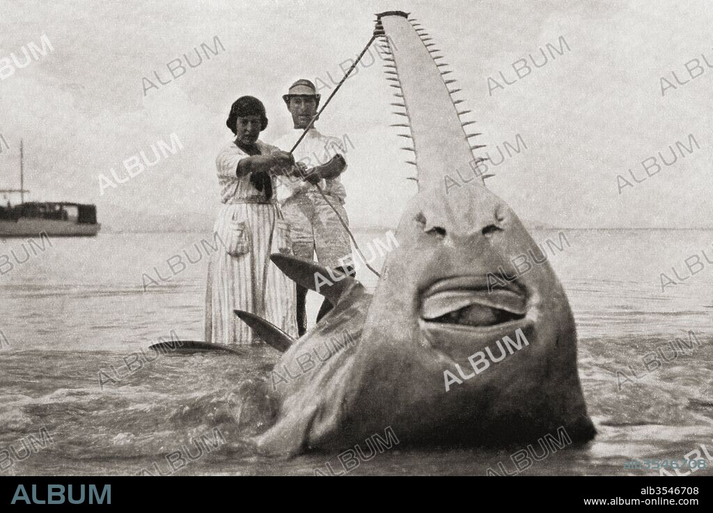 Frederick Albert Mitchell-Hedges, aka Mike Hedges, 1882 - 1959. English adventurer, traveler, and writer, seen here in the 1920's with his companion, Lilian Mabel Alice, aka Mabs, née Roussel, Lady Richmond-Brown, 1885-1946, with their record catch, a sawfish weighing 5,700 lbs. From Heroes of Modern Adventure, published 1927.