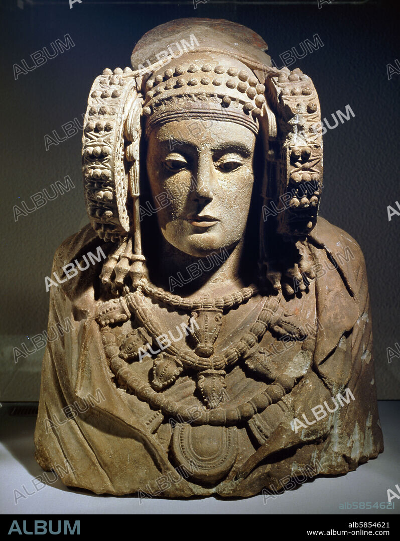 Lady of Elche. Painted limestone bust; from L'Alcúdia, Spain; 4th century BCE. The famous but controversial " Lady of Elche" (Dama d'Elx in Catalan, Dama de Elche in Spanish) is a polychrome stone bust that was revealed as found by chance in 1897 at L'Alcúdia, an archaeological site that was on a private estate about 2 km, south of Elx (Spanish Elche) (Alicante, Land of Valencia, Spain). The Lady of Elx is generally believed to be Iberian art of the 4th century BCE, or of the Hellenistic or the Roman periods. The bust is usually thought to represent a woman wearing a very complex headdress and big coils on each side of the face. A minority interpretation sees it representing a man.