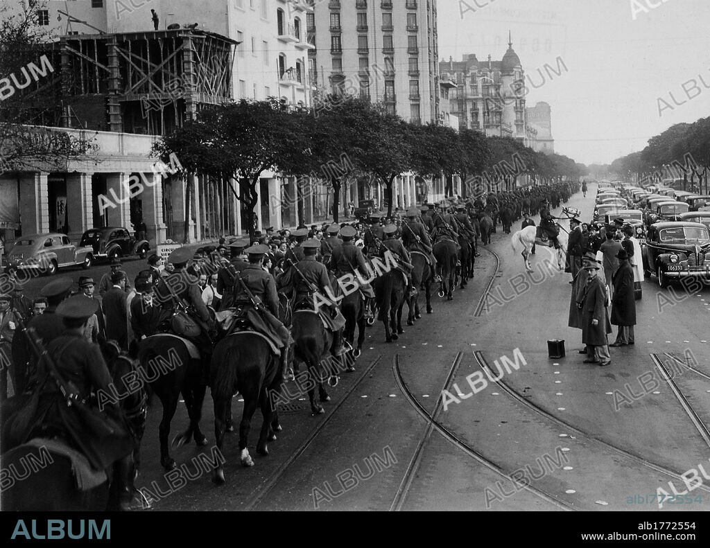 Parade of mounted soldiers. A parade of mounted soldiers passing along the city streets near a small group of observers. Buenos Aires, June 1943.