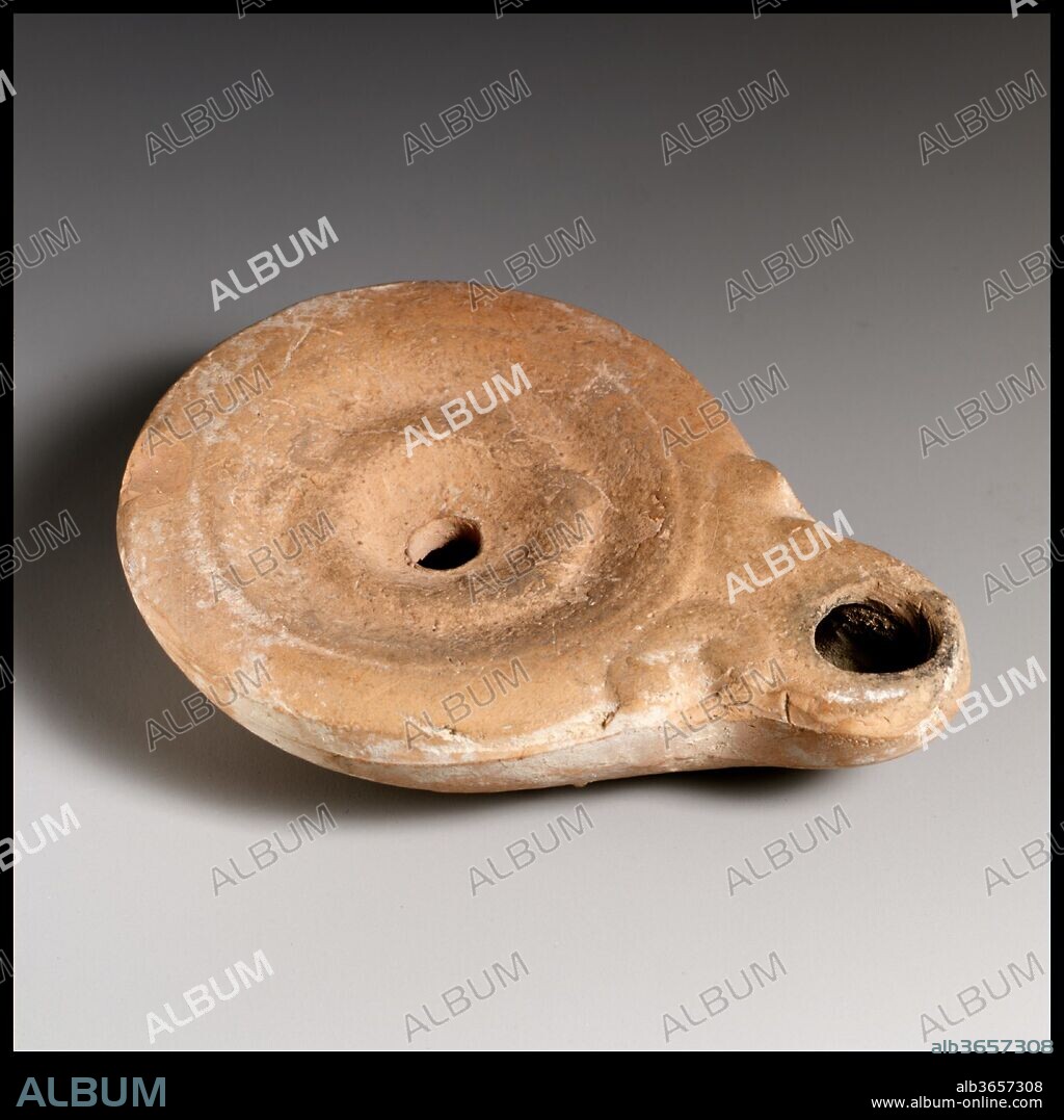 Terracotta oil lamp. Culture: Roman, Cypriot. Dimensions: Overall: 1 x 3 3/4 in. (2.5 x 9.5 cm).
Loeschcke Type 4. Mold-made. Discus: indistinct wreath around central filling hole, with small taenia opposite nozzle. Plain shoulder. Volutes flanking nozzle. On left side of body: raised, molded letters in retrograde: ZW. Slightly raised base ring and flat base.