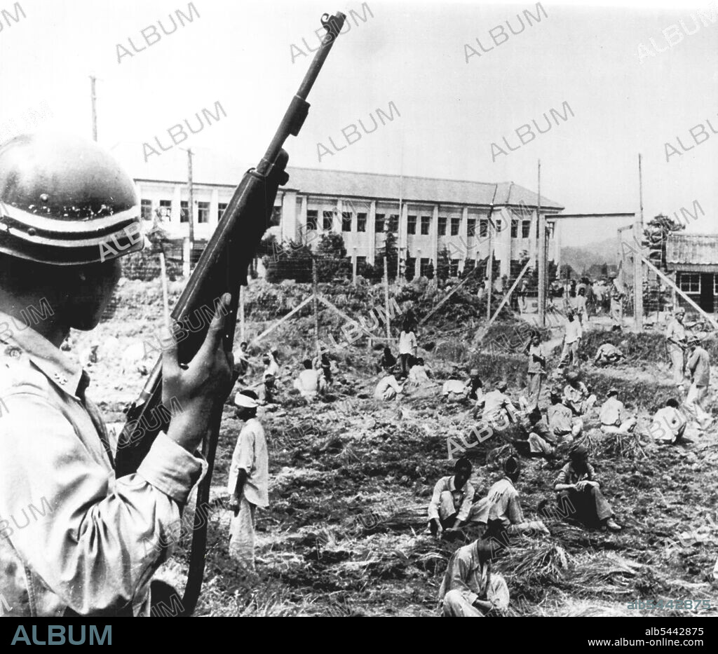 Captured North Koreans -- A South Korean military policeman stands guard over North Korean prisoners in an enclosure near Pusan. The majority of the prisoners are working to clear the ground for the new prison camp. September 14, 1950. (Photo by AP Wirephoto).