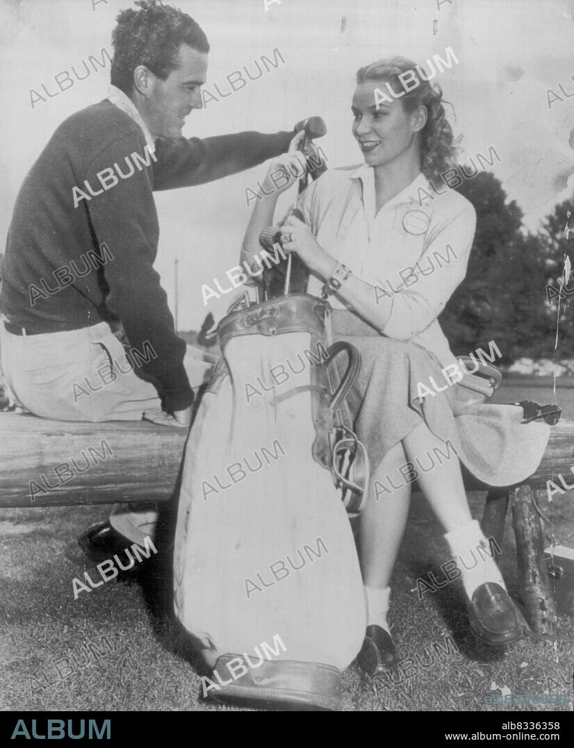 Sweeny and wife at masters -- Robert J. Sweeny, Jr., former British amateur  golf champion, gets a helping hand from his bride in polishing up his clubs  after the first rou -