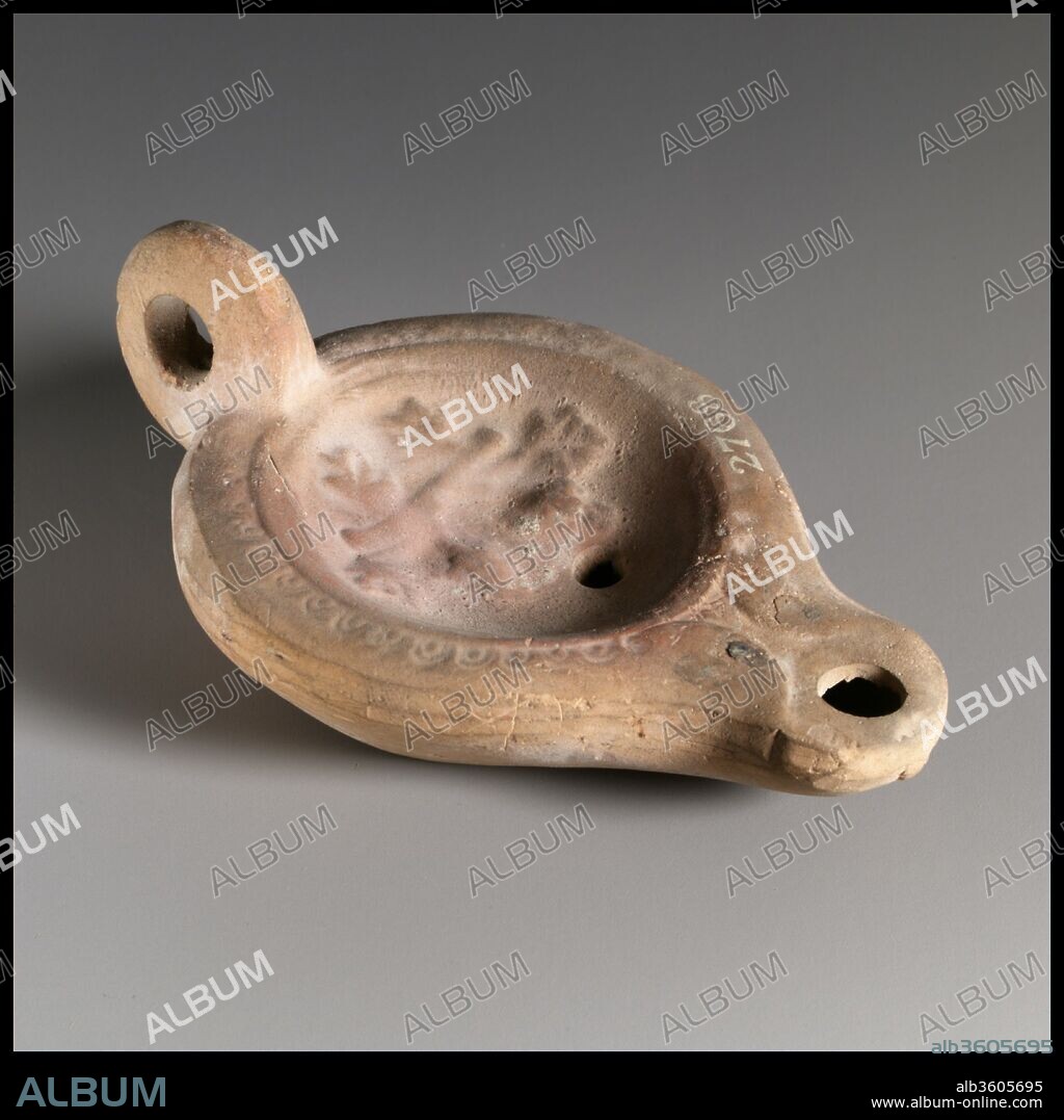 Terracotta oil lamp. Culture: Roman. Dimensions: Overall: 1 3/8 x 3 5/8 in. (3.5 x 9.2 cm). Date: 2nd century A.D..
Loeschcke Type 5. Mold-made, with ring handle. Discus: a horizontal branch with oak leaves above and below; a single, small filling hole near front and with a band of grooves and raised lines at edge of discus. On narrow, almost horizontal shoulder, a pattern of small ovules. Volutes flanking nozzle. Broad raised ring base, outlined by two incised circles, and a slightly concave base, with a vertical impression at center.
Intact.