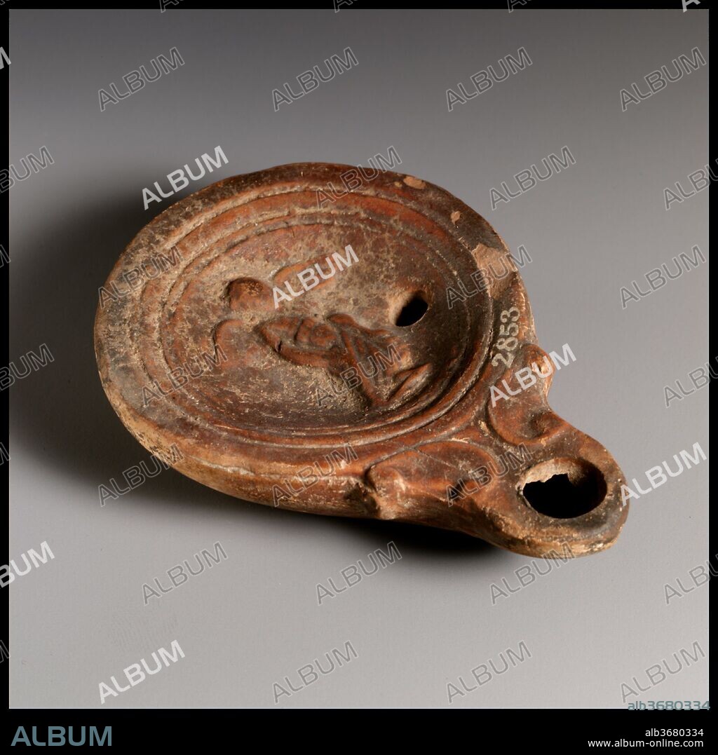 Terracotta oil lamp. Culture: Roman, Cypriot. Dimensions: Overall: 7/8 x 3 5/8 in. (2.2 x 9.2 cm). Date: ca. A.D. 40-100.
Loeschcke Type 4. Mold-made. Discus: Eros, facing forward, with outspread wings and wearing drapery around his lower body and legs, standing on small ground line. Base ring and slightly concave base.