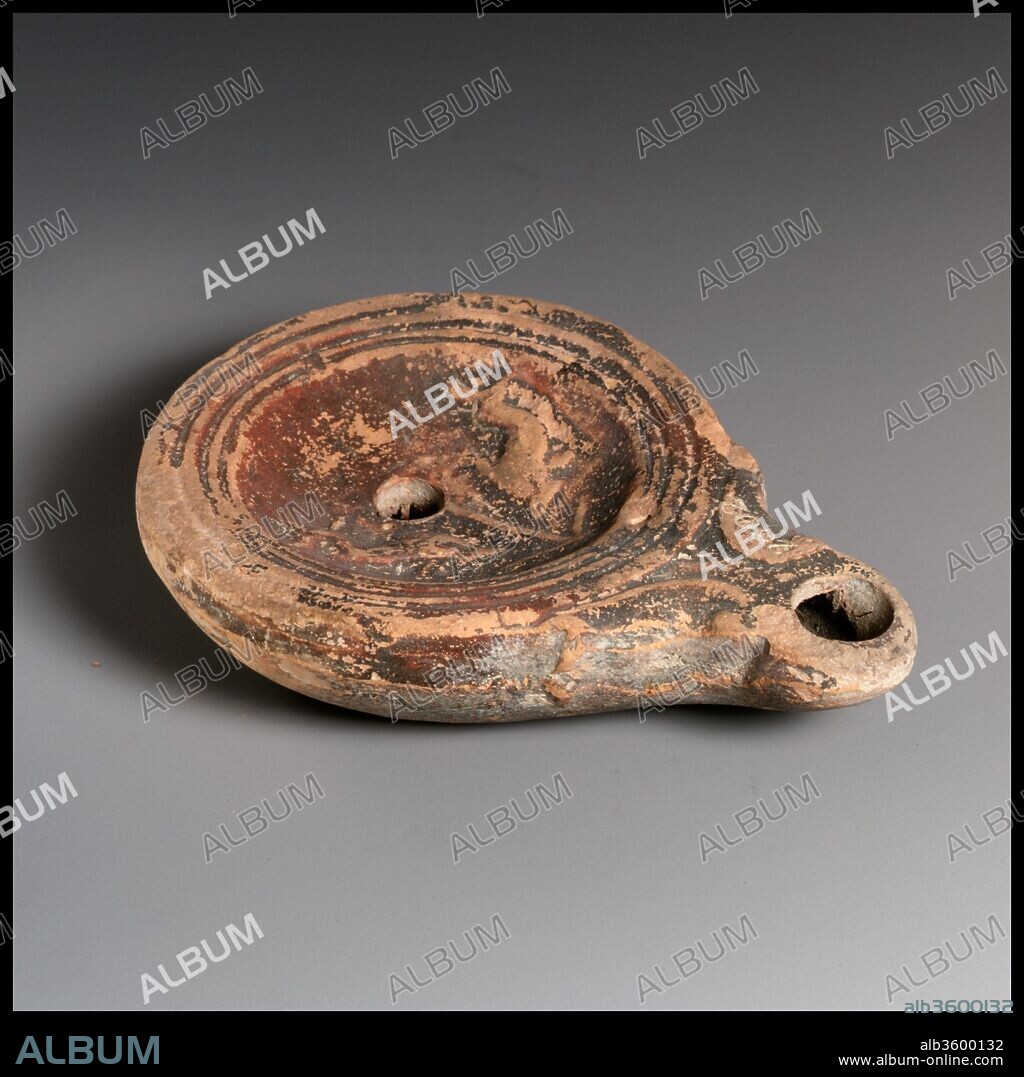 Terracotta oil lamp. Culture: Roman. Dimensions: Overall: 7/8 x 3 5/8 in. (2.2 x 9.2 cm). Date: 1st century B.C.-1st century A.D..
Loeschcke Type 4. Mold-made. Discus: two dolphins, facing downward, flanking a vertical anchor; a single filling hole at center obscuring the top of the anchor, and a band of lines and grooves at edge. Small volutes flanking nozzle. Incised base ring, and slightly uneven base.
Intact.