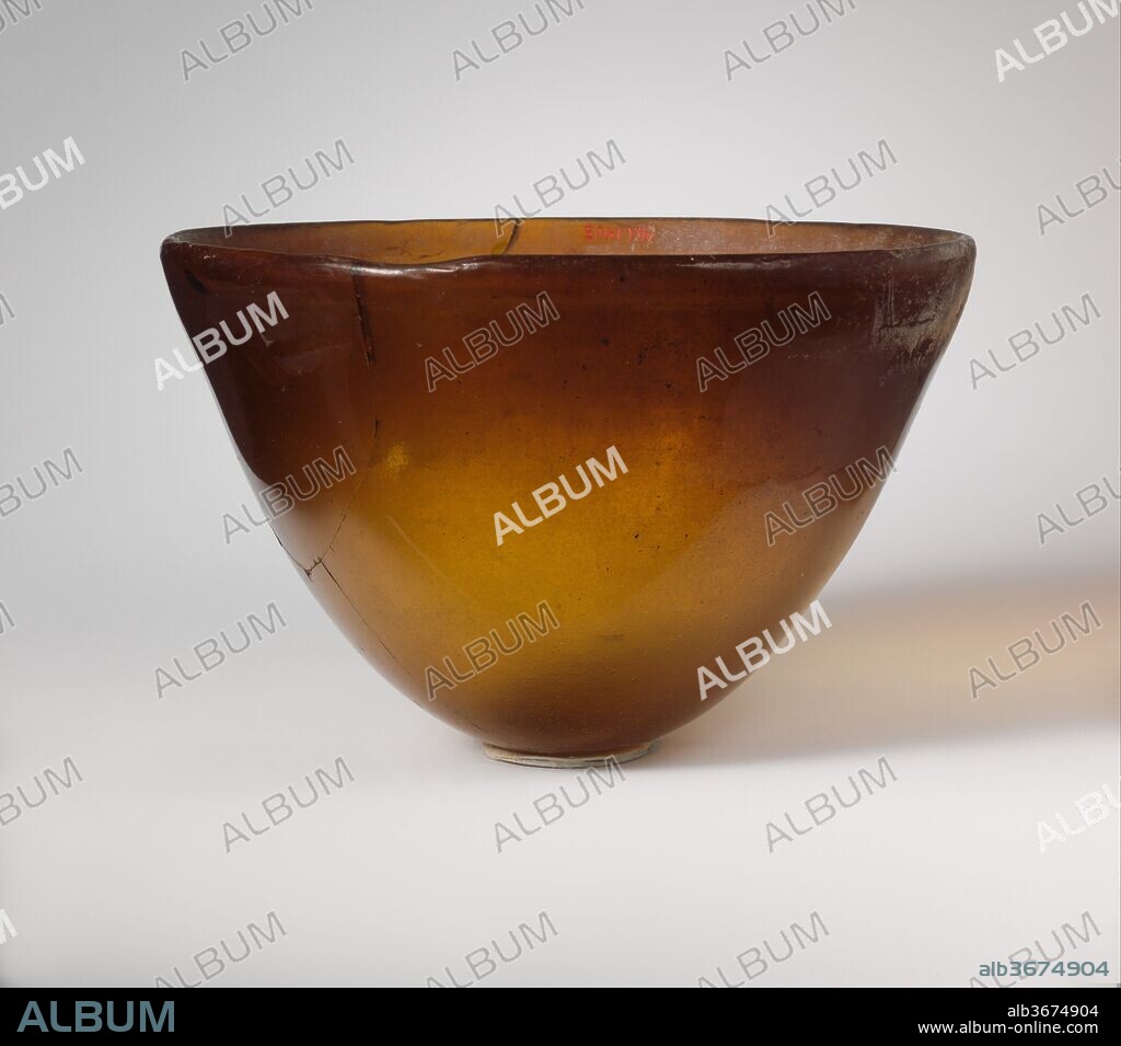 Glass conical bowl. Culture: Greek, Syro-Palestinian. Dimensions: H.: 2 7/8 in. (7.3 cm)
Diam.: 6 in. (15.2 cm). Date: mid-2nd-early 1st century B.C..
Translucent honey brown.
Upright rounded but uneven rim; undulating side, tapering diagonally downward; convex bottom.
On interior, a single horizontal groove below rim, cut irregularly.
Broken and repaired, with one hole and several chips in side; internal strain cracks around rim; some bubbles; one patch of whitish iridescent weathering below rim on exterior, and dulling and faint weathering on interior.
Rotary grinding marks on interior; some irregular tooling marks below rim on exterior.