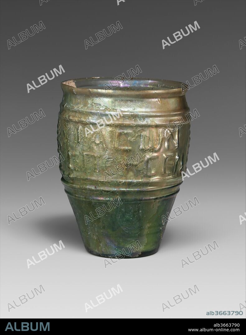 Glass beaker signed by Jason. Culture: Roman, Syro-Palestinian. Dimensions: Height: 3 9/16 in. (9.1 cm)
Diameter: 2 5/8 × 2 9/16 in. (6.7 × 6.4 cm). Date: mid-1st century A.D..
Translucent green.
Outsplayed knocked-off rim with indent below; body with convex sides, tapering downwards; flat bottom, recessed within rounded edge.
Three-part mold with two vertical sections joined to cup-shaped bottom section, forming decoration in relief on sides and bottom; two horizontal ridges above central frieze containing two Greek inscriptions, each in two lines and divided vertically by a stylized palm frond; below frieze, three more horizontal ridges; near bottom on cup section of mold, two more horizontal ridges; on bottom, raised circle surrounding central depression with small boss.
Intact except for one small chip in rim; blowing striations, some pinprick and a few larger bubbles; dulling, pitting, and brilliant iridescent weathering on exterior, and thick creamy brown weathering with soil encrustation on sides of interior.
The inscriptions read "Jason made (me/it)" on one side and "May the buyer be remembered" on the other.
Molded into the sides of the beaker are two Greek inscriptions. One says Jason made [me or it], and the other seems to be an echo of a Semitic blessing, Let the buyer remember. The two may be read separately, but it is more logical to see them as a commercial slogan, Let the buyer remember [that] Jason made [this beaker], thereby encouraging customers to buy Jason's products again.