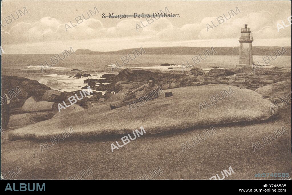 1931. Abalar stone in Muxia, with the villain cape and its great Lighthouse in the background.