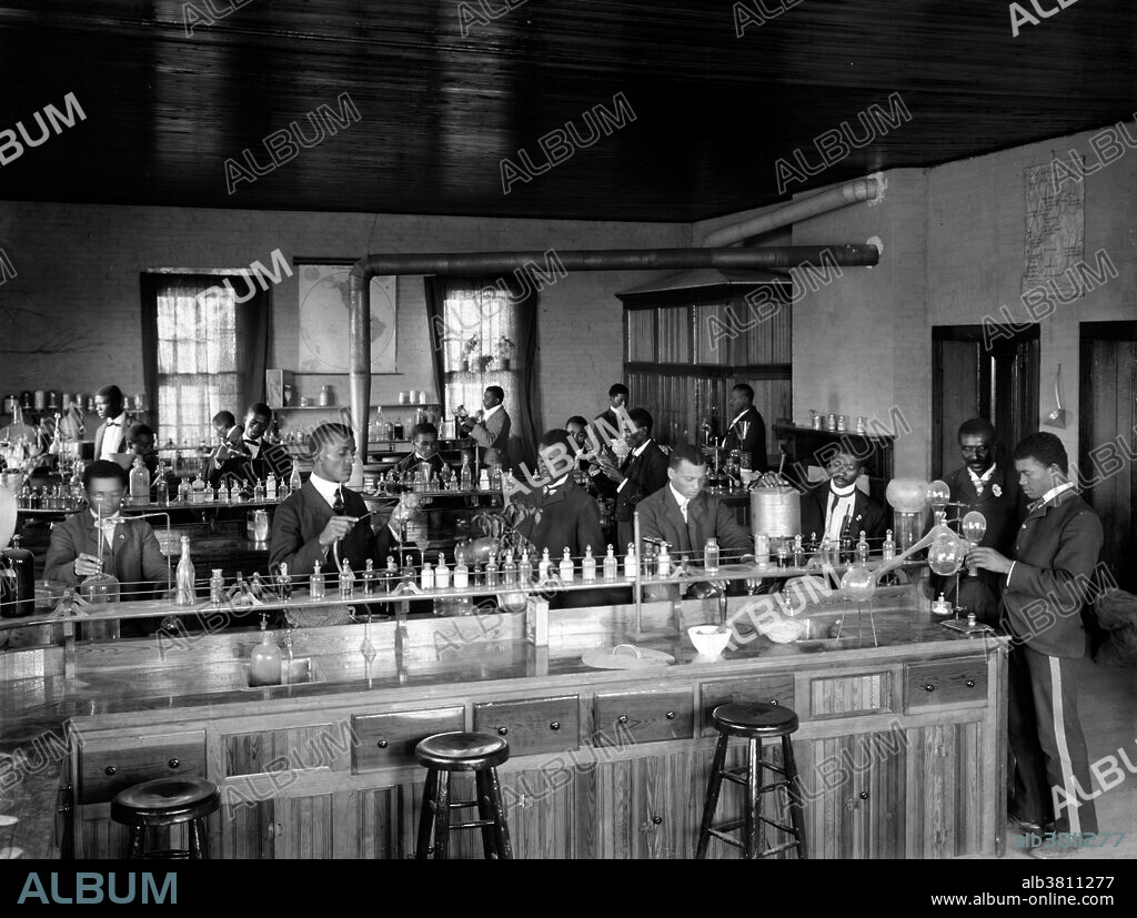 Chemistry laboratory/classroom with students at the Tuskegee Institute, Tuskegee, Alabama. George Washington Carver stands second from right, facing front (framed by doorway). George Washington Carver (1864 - January 5, 1943) was an African-American scientist, botanist, educator, and inventor born into slavery. In 1891 he attended and studied botany at Iowa State Agricultural College where he was the first black student, and later taught as the first black faculty member. His reputation is based on his research into and promotion of alternative crops to cotton, such as peanuts, soybeans and sweet potatoes, which also aided nutrition for farm families. He wanted poor farmers to grow alternative crops both as a source of their own food and as a source of other products to improve their quality of life. As an agricultural chemist, Carver discovered three hundred uses for peanuts and hundreds more for soybeans, pecans and sweet potatoes. He died in 1943, at the age of 78. In 1977, he was elected to the Hall of Fame for Great Americans. In 1990, he was inducted into the National Inventors Hall of Fame. Carver is often referred to as "Father of Chemurgy". Photographed by Frances Benjamin Johnston, 1902.