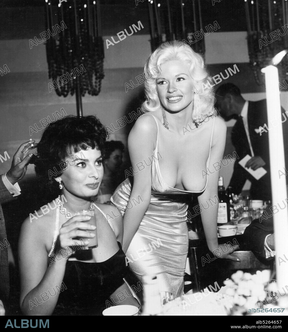 JAYNE MANSFIELD and SOPHIA LOREN. American actress and model Jayne Mansfield, known for her publicity stunts, attended a dinner at the exclusive Beverly Hills Romanoff's restaurant hosted by Paramount Pictures to officially welcome Italian actress Sophia Loren to Hollywood. A photograph of the two women, with Loren casting a sideways glance at Mansfield's cleavage, was distributed world-wide and became an international sensation.