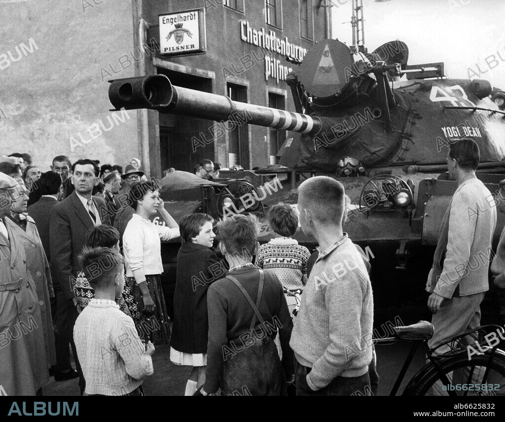 West Berlins standing at a heavy Patton tank of the US Army on 23rd August 1961 at checkpoint Friedrichstraße in the western part of Berlin. From the 13th of August in 1961, the day of the construction of the Wall, until the fall of the Wall on the 9th of November in 1989, the Federal Republic of Germany and the GDR were seperated into West and East by the Iron Curtain. 23/08/1961