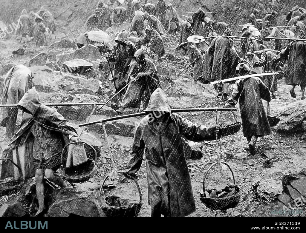 China: A team of workers labouring in a stone quarry in heavy rain 
