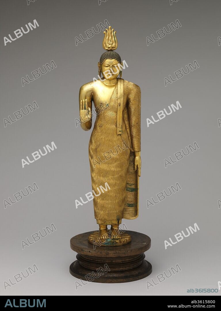 Buddha. Culture: Sri Lanka, Kandy district. Dimensions: H. (figure) 23 3/8 in. (59.4 cm); H. (incl. base) 25 9/16 in. (65 cm) W. 8 11/16 in. (22 cm). Date: 18th century.
This work represents Kandyan-period Buddha imagery at its finest. The figure's physique is robust, and the full face lacks the softness of features found in lesser works of the period. Auspicious marks (lakshana) appear here, and the lowered left arm is a convention that persisted throughout the later Kandyan period.