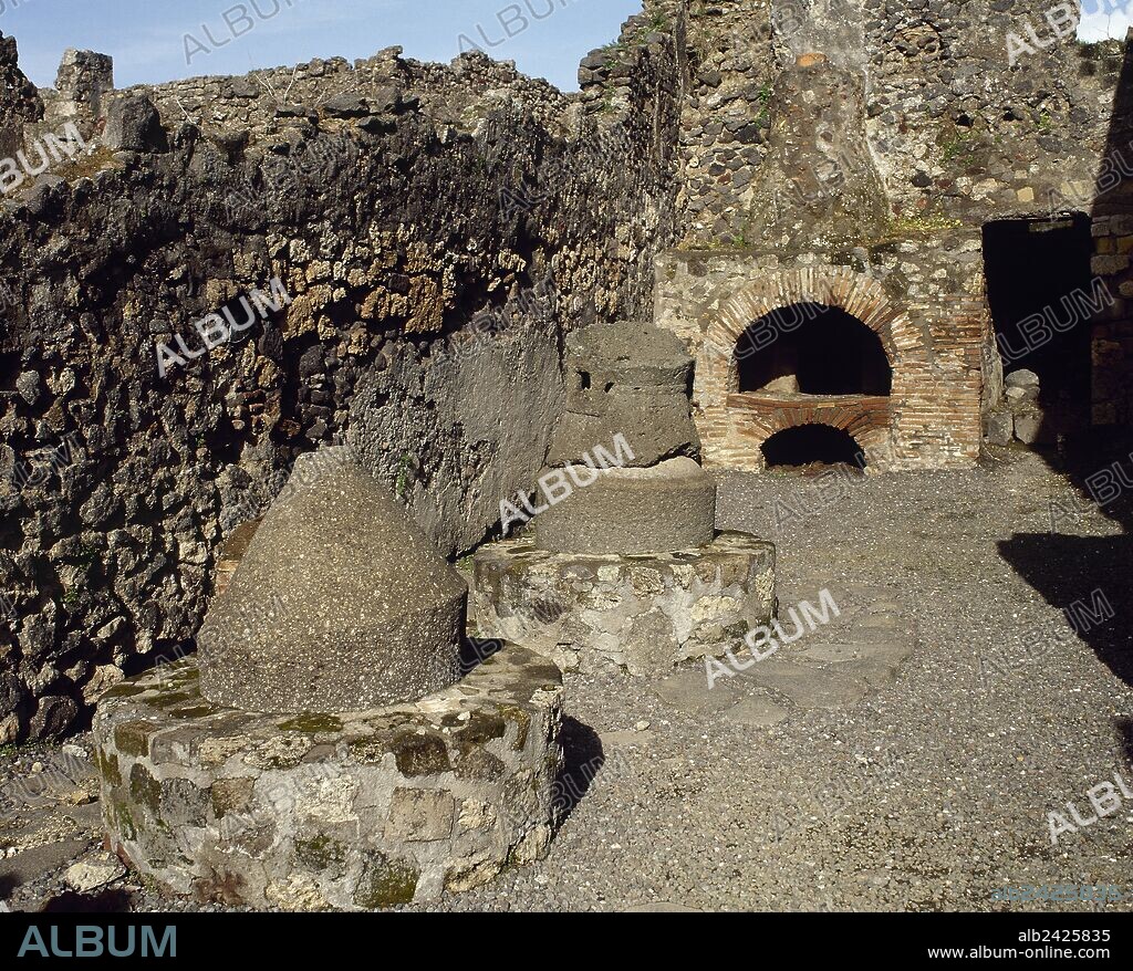 Italy. Pompeii. Bakery (Pistrium). View of the establishment. Millstones made of basalt lava, driven by donkey to grind the grain, oven for the bread and the fireplace of the oven. Campania.