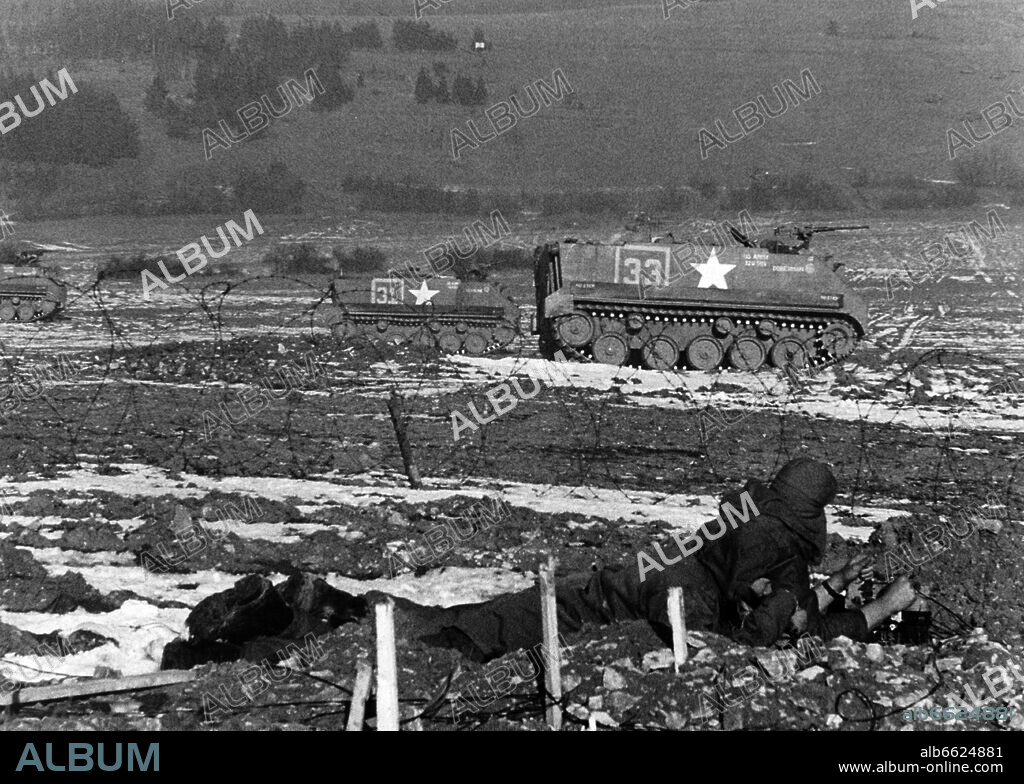 A soldier of the US army looks at a unit of armoured carriers in offensive position during a big winter manoeuvre of the US army on the military training area Grafenwöhr on 5 February 1959. The highlight of the manoeuvre, in which around 60.000 soldiers participated, was a simulation of a nuclear attack observed from the "Feldherrenghügel" by around 40 NATO generals. 05/02/1959