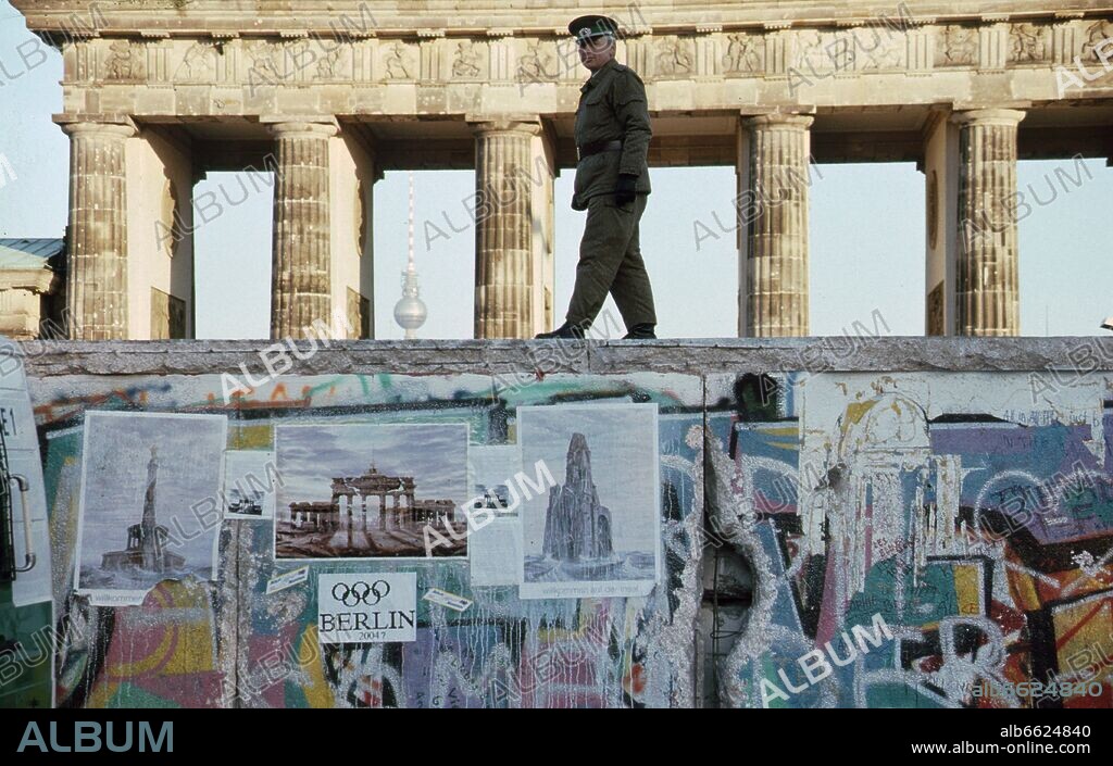 Opening of the Berlin Wall - East German NVA border guard is walking on top of the wall in the Western side of the separation barrier at the Brandenburg Gate, looking at the Western part of the city on NOvember 16th 1989. Photo: Sven Barten (c) dpa - Report. 16/11/1989