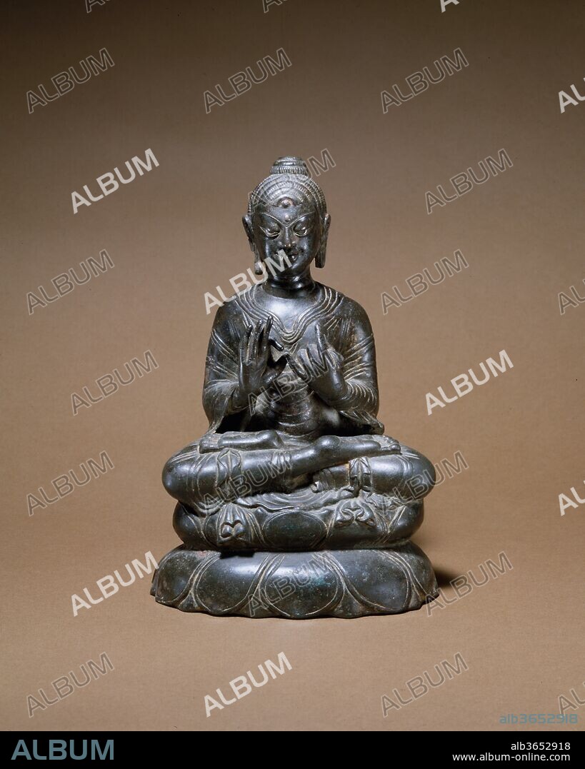 Preaching Buddha. Culture: India (Jammu & Kashmir, ancient kingdom of Kashmir) or Pakistan. Dimensions: H. 8 3/8 in. (21.3 cm). Date: 8th century.
This Buddha, with his legs folded in a full yogic posture and his hands gesturing preaching, invokes the first sermon at Sarnath. The complex treatment of the monastic robes, most notably their pleated ends, is evidence of an unidentified monastic workshop, probably located in Kashmir or the Swat Valley. The treatment of the hair curls is unconventional, as is the extreme stylization of the eyes and eyebrow. Silver inlay marks the eyes and auspicious forehead mark (urna).