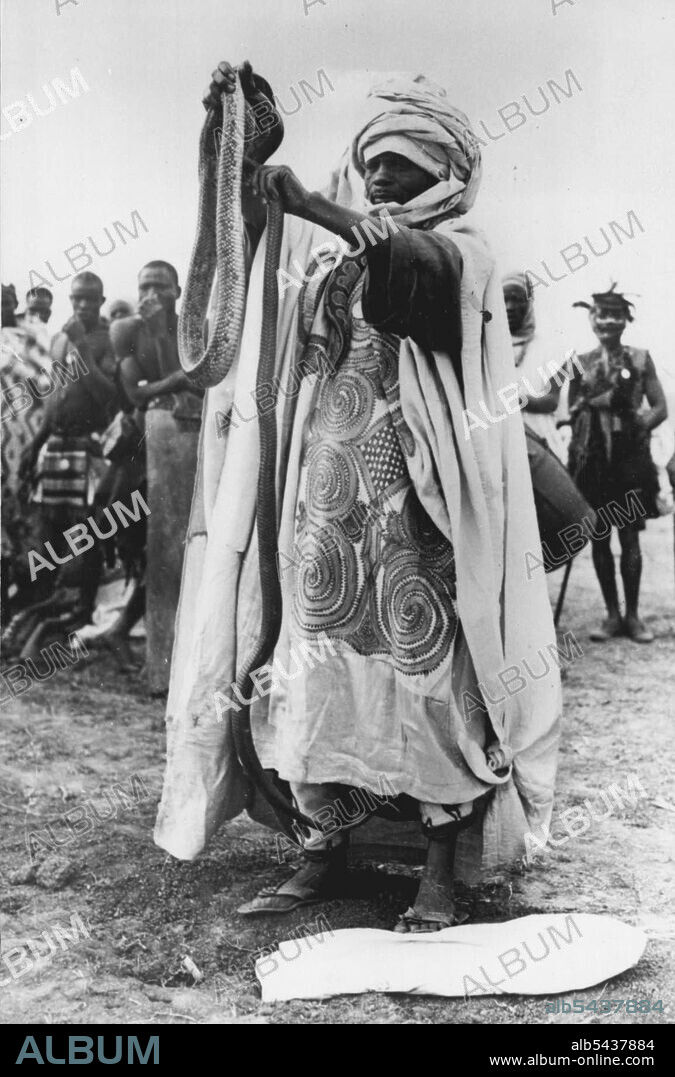 The Royal Tour In ia -- A superbly dressed native tribesman gives a remarkable display of snake charming before H.M. The queen and the Duke of Edinburgh. One of the most picturesque events of the Royal tour in ia was the great Durbar held by H.M. The Queen during her visit to Kaduna, capital of the Northern Region of ia. February 14, 1955. (Photo by Sports & General Press Agency Limited).;The Royal Tour In ia -- A superbly dressed native tribesman gives a remarkable display o.