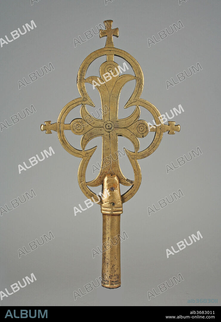 Processional Cross. Culture: Amhara or Tigrinya peoples. Dimensions: H. 12 13/16 x W. 6 11/16 in. (32.5 x 17 cm). Date: 13th-14th century.
Ethiopian Orthodox Churches retain a variety of crosses for use in liturgical ceremonies. Among the most common are crosses outfitted with sockets, such as this example, which could be mounted on a staff and carried during services or processions. The juxtaposition of positive and negative space employed in the cross would have created a dramatic silhouette against the sky during an outdoor procession, or cast an imposing shadow during a candlelit service.
Like all Ethiopian crosses, this cross was made by a monk at the request of an elite patron. Wealthy devotees commissioned gifts to bestow upon monasteries to receive prayers and increase their reputation, as well as to support the faith. The majority of Ethiopian crosses were cast in brass using the lost-wax casting technique. Because it allows for only one of each object to be created, the technique may have contributed to the innumerable diversity of Ethiopian metal crosses.
In this example, a trifoliate cross has been inscribed in a quatrefoil frame. Both the cross and its frame are further ornamented with incised lines and punctuated concentric circles at the middle and three terminals of the cross. Images of Christ are rare in Ethiopian crosses, reflecting Ethiopian Orthodoxy's dual belief in the cross as a sign of the Crucifixion and the Tree of Paradise. Thus, the small pattée crosses sprouting from the summit and sides of the frame may allude to budding leaves. Trifoliate crosses became common in northern Ethiopia beginning in the twelfth century, with comparable examples found in the celebrated churches of Yemrehenna Kristos and Lalibela.
Kristen Windmuller-Luna, 2014.