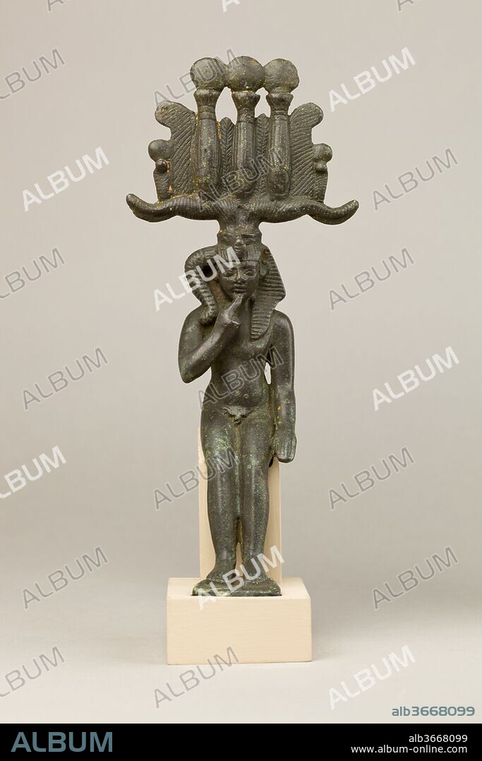 Child god in nemes and hemhem crown. Dimensions: H. 22 cm (8 11/16 in.); W. 10.6 cm (4 3/16 in.); D. 7.2 cm (2 13/16 in.). Date: 664-30 B.C..
The figure represents a child god in a seated/reclining position, wearing the hemhem crown with the nemes. The hemhem crown was cast separately from the child god, and was inserted and secured at the top of the head. The child god is usually distinguished from adult gods by a range of iconographic clues: his nudity, the finger raised to the mouth (a child-like gesture), and the thick sidelock attached on the right side of his nemes. Here the figure's hands are both held at the sides, but his nudity and sidelock suffice to identify him as a child god. Child gods are commonly linked with royalty and this god's hemhem is an elaborate royal crown with solar associations, here emphasized not just by the sun disks at the top of the crown, but also by incised sun disks at the base of each hem element. Meanwhile, the child god's plump, well-fed belly showcases his ability to bring about prosperity and abundance.
Child gods grew in popularity and cult from the Third Intermediate Period onwards, rivaling even the most powerful and ancient gods, especially as temple offerings. The best known is Horus the Child (Harpokrates), who was the son of Isis and Osiris, but many others existed, including Khonsu the Child, Ihy, and Harsiese, among others. Thus it is difficult to assign a precise identity to this statuette without an associated inscription.