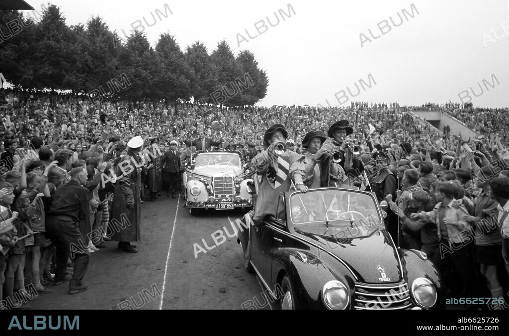 Enthusiastic welcome for the German internatinoal player Max Morlock (middle, back car) in Nuremberg's stadium on the 7th of July in 1954 in front of 30,000 spectators. Morlock is waving from the back car to young students. The German national football team with Morlock had sensationally won the 1954 FIFA World Cup final 3:2 against Hungary, for the first time winning a world cup title. Popular attacker Morlock had scored the 1:2 reducer. 07/07/1954