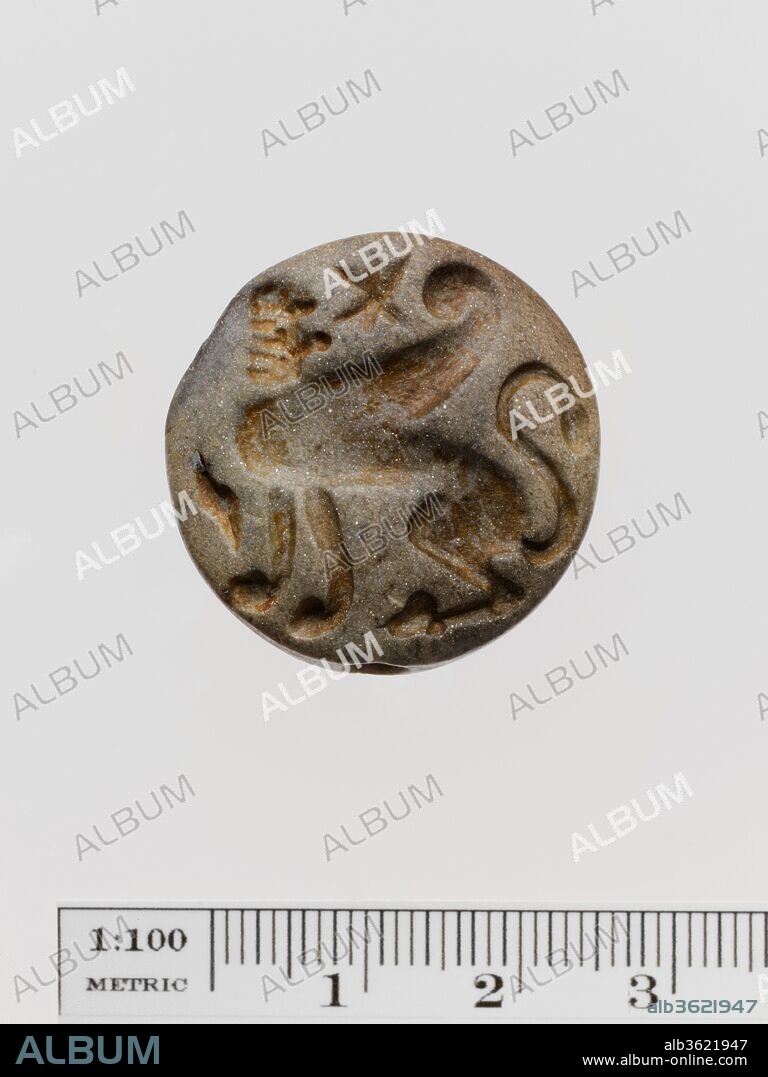 Micaceous stone lentoid seal. Culture: Greek, Melian. Dimensions: Diameter 2.7 cm. Date: 2nd half of the 7th century B.C..
Sphinx, with recurving wing, tufted tail and head turned back; long hair is carved in horizontal layers; Daedalid fashion.